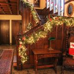 The grand staircase in the Manor House entrance decorated with holiday lights and evergreens