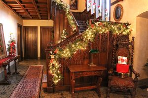 The grand staircase in the Manor House entrance decorated with holiday lights and evergreens