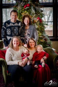 Family sitting on loveseat in front of holiday tree
