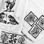 Black block print nature themed designs on a white towlels