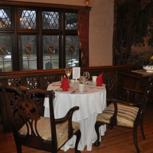 A table for two with a white tablecloth, set for dinner, overlooks a window at the W.K. Kellogg Manor House.